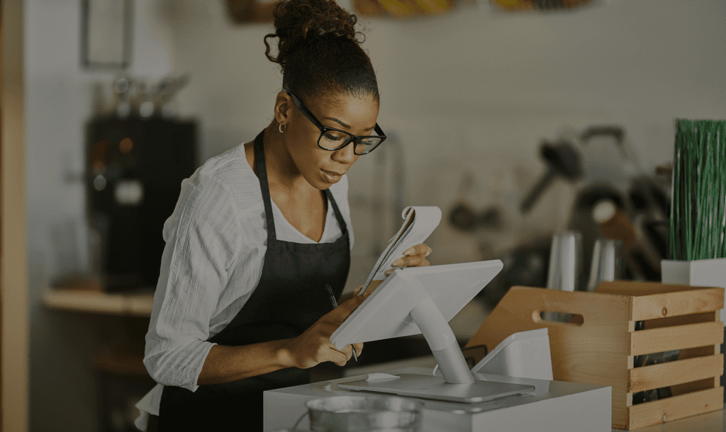 A woman at a digital point-of-sale system reviewing documents